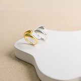 Product image of sterling silver teardrop ring next to gold plated sterling silver ring against white and beige background.