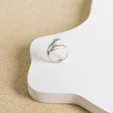 Product image of sterling silver teardrop statement ring against white block and beige background.