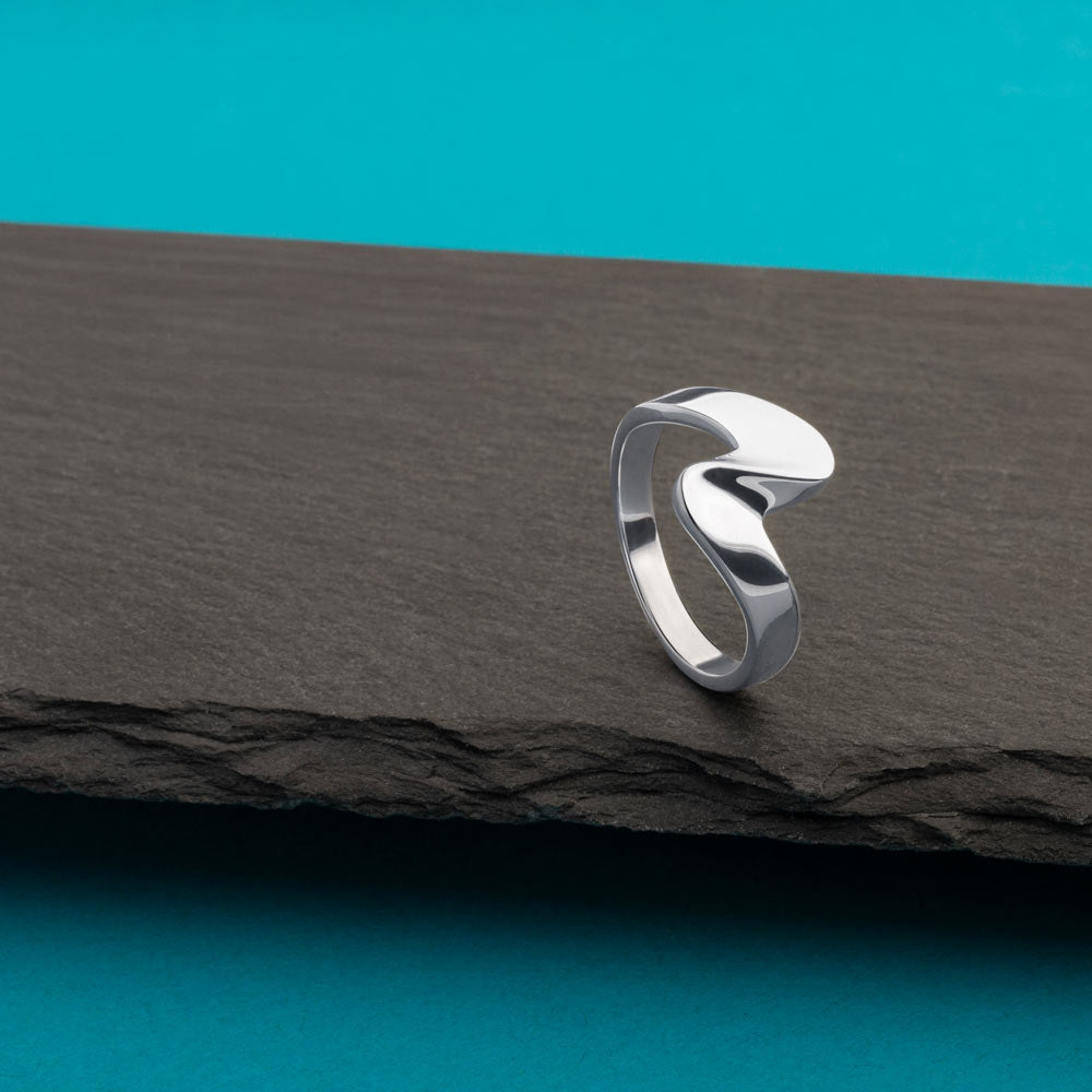 An image showing one silver wave ring placed on a balck and blue background.