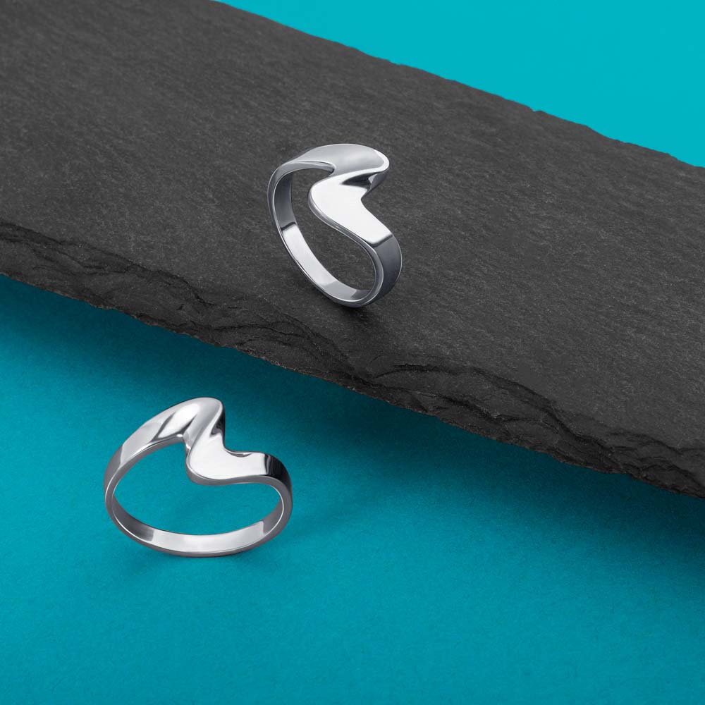 An image showing two silver wave ring placed on a balck and blue background.