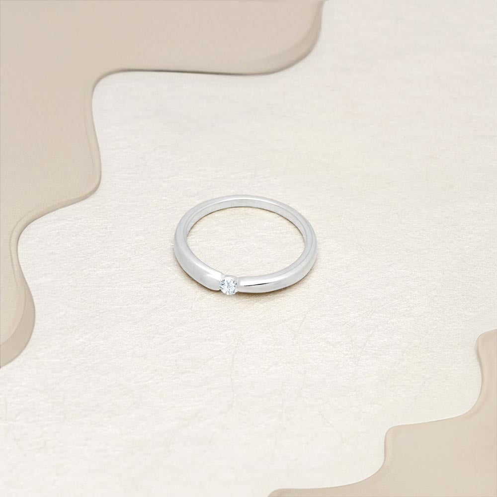 Silver solitaire wedding band with CZ stone in 3mm placed on a beige surface.