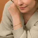 A close-up of a woman's hand wearing a sleek paperclip bracelet