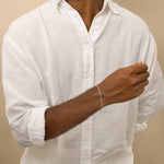 A man wearing white shirt showcasing the gold paperclip bracelet