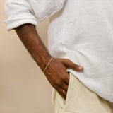 A  man with his hand in his pocket wearing gold paperclip bracelet