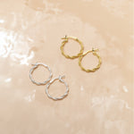 Marketing image of Silver and Gold plated Textured Hoops with post notch againts beige-brown tile.