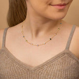 A woman wearing gold plated colourful charm necklace around her neck in brown top