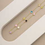 An image showing gold plated colourful charm necklace placed on a beige and white background