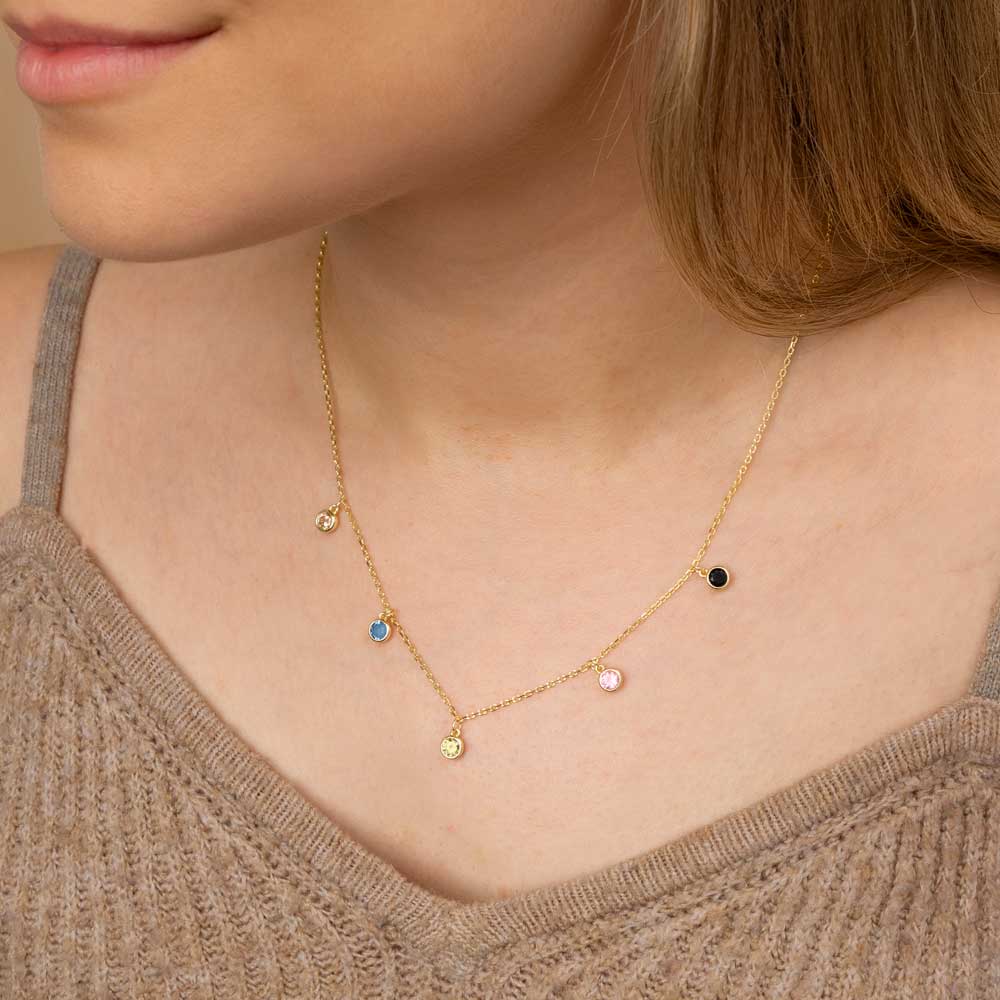 A woman wearing gold plated colourful round hanging charm pendant necklace around her neck in brown top