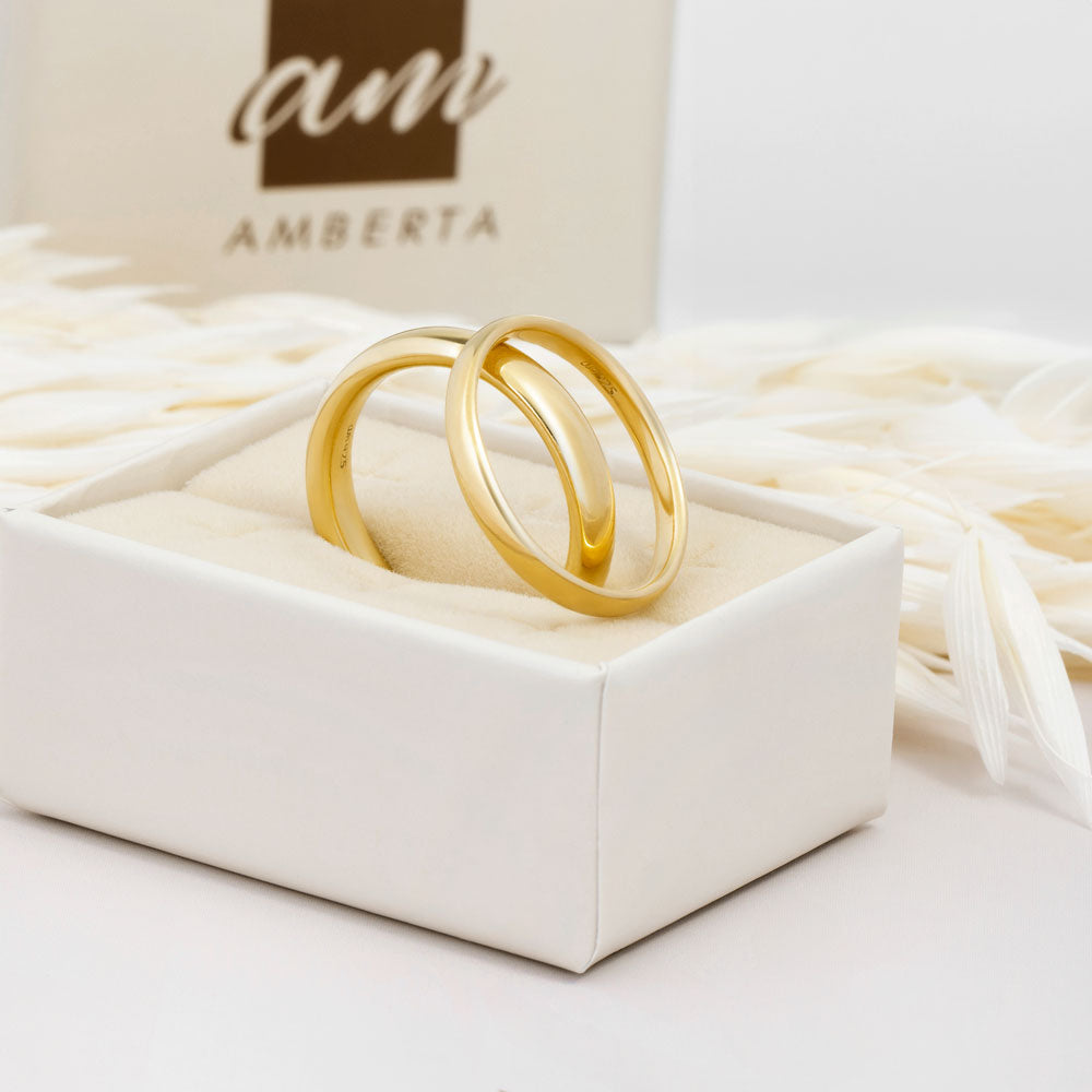 An image showing two gold plated wedding band in 2.5mm and 4mm thick placed on beige and white background.