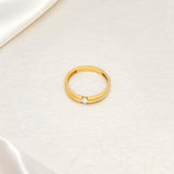 Gold plated solitaire wedding band with CZ stone in 3mm placed on a beige surface.