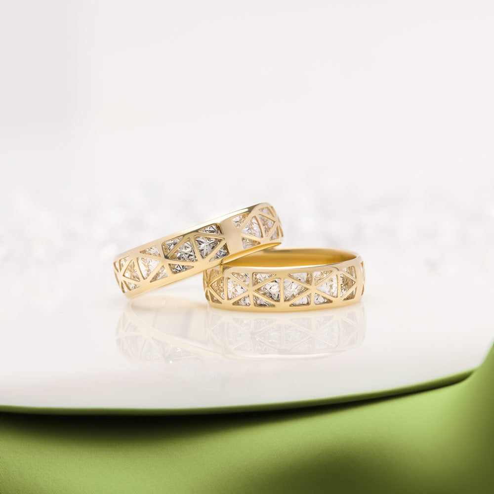 Two 14ct gold Geometric Filigree statement rings placed on a white and green surface.