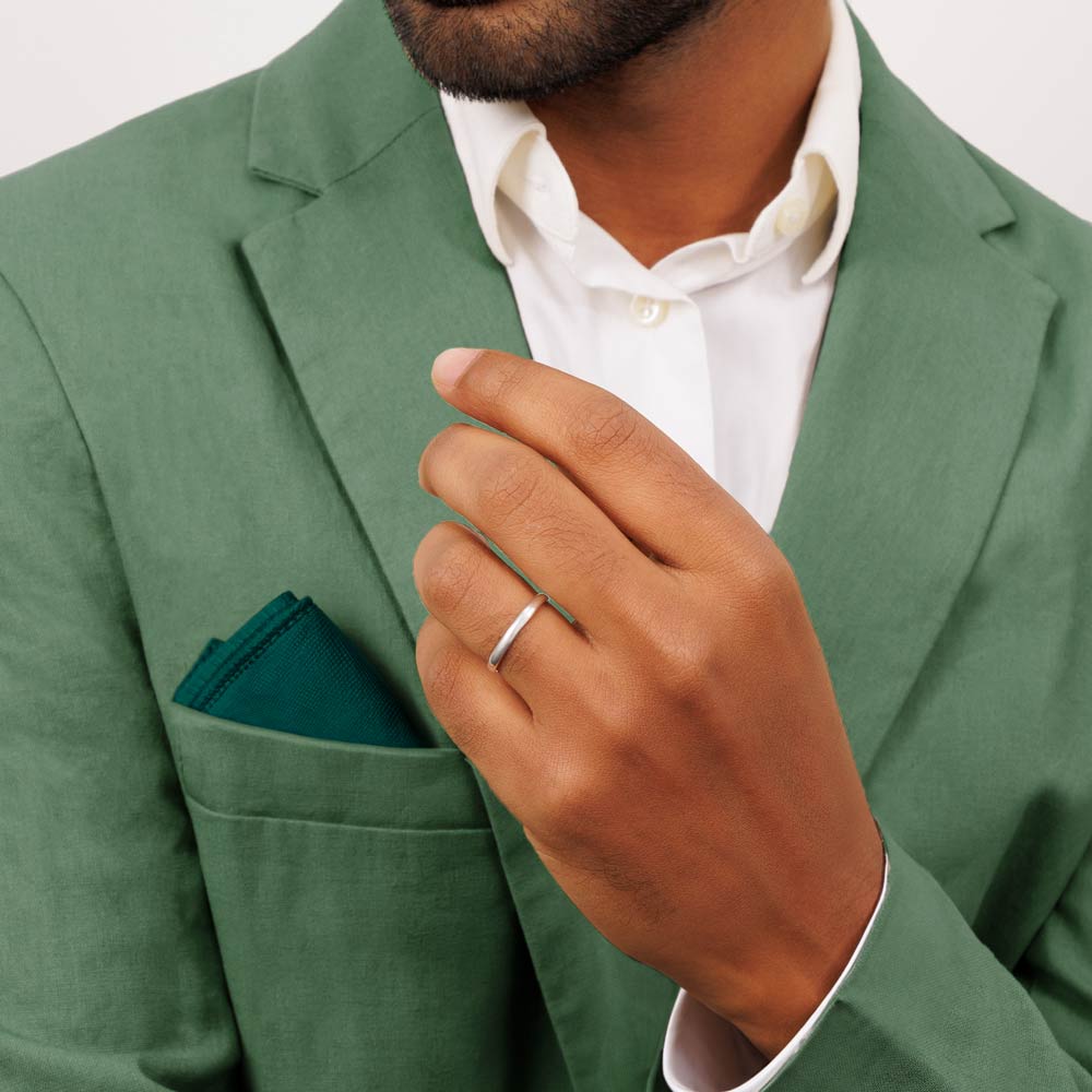 A man wearing a green suit and white shirt showing a 9ct white gold wedding band 2.5mm