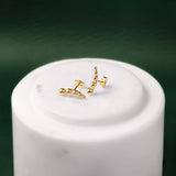 Two Shining gold balls crawler earrings against a white and green background