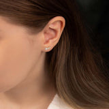 A woman in a white shirt wearing an elegant yellow and white gold crawler earring featuring cubic zirconia