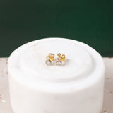 Two elegant yellow and white gold crawler earrings featuring cubic zirconia against a white and green background