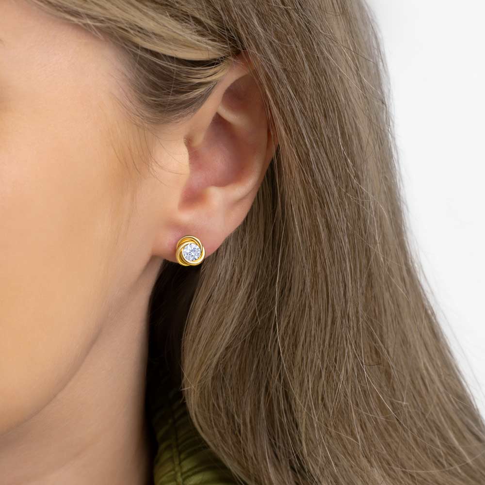  Close up picture of a woman wearing gold knot with Cubic Zirconia studs earring