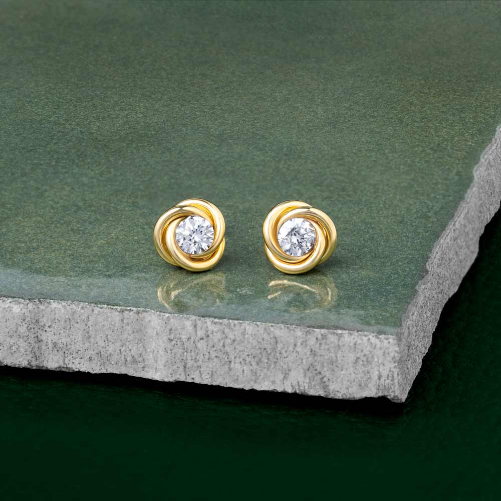9 Carat Gold Knot studs placed on a contrasting dark green tile
