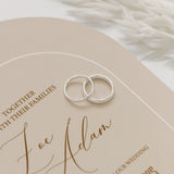 Two elegant wedding rings placed delicately on an elegant wedding invitation