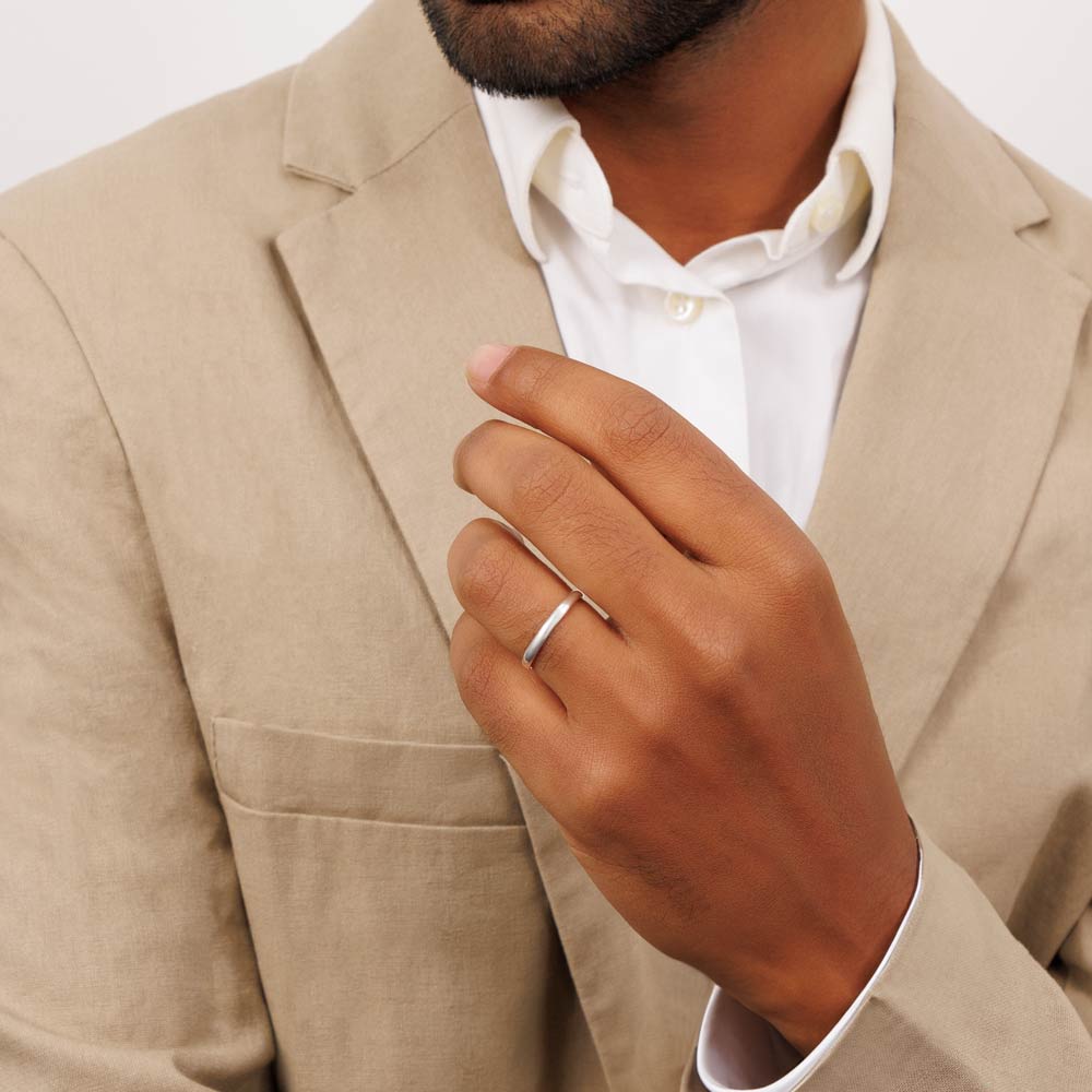 The groom dressed in a tan suit proudly displays his wedding ring