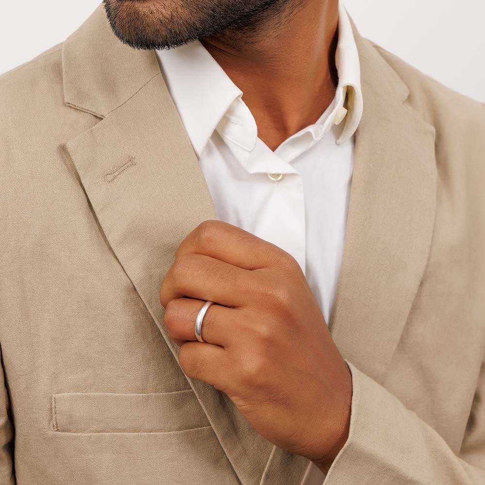 Groom adjusts his suit showcasing silver wedding band