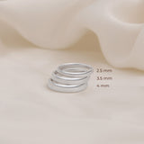 Three silver rings of different thickness 2.5mm 3.5mm 4mm placed over other to show its size difference